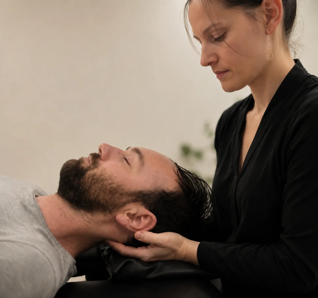 Bryhnn Freitas giving a hands-on neck treatment to a client lying on the treatment table.